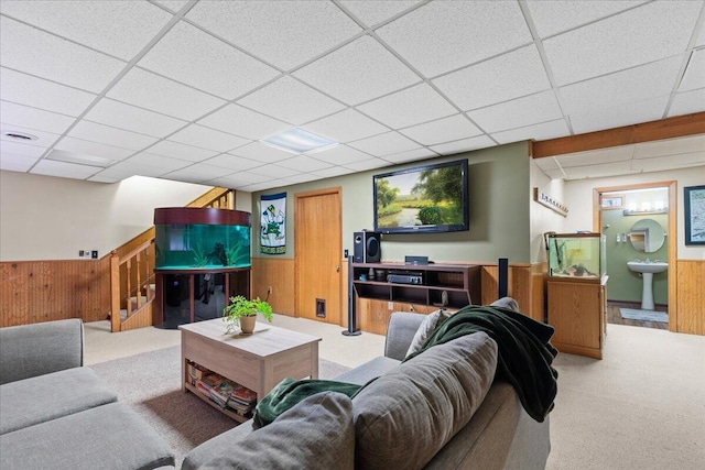 1021 Aspen Pl, West Bend, WI 53095 - carpeted living area featuring a paneled ceiling, wooden walls, a wainscoted wall, and stairs