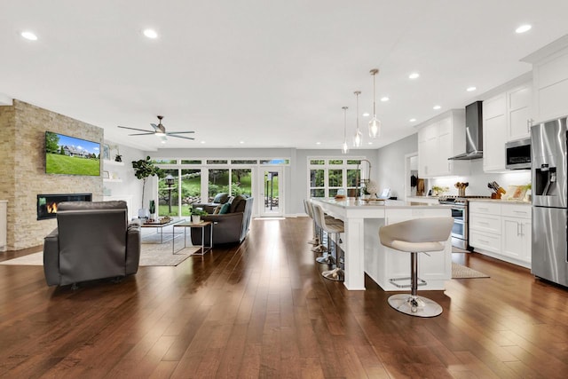 742 Charolais Dr, Slinger, WI 53086 - kitchen with stainless steel appliances, wall chimney range hood, open floor plan, a ceiling fan, and recessed lighting