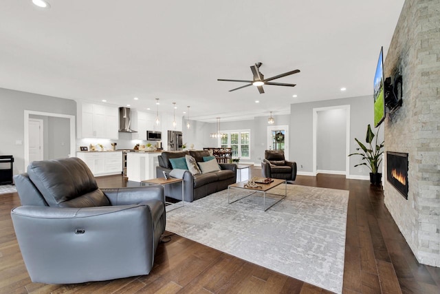 742 Charolais Dr, Slinger, WI 53086 - living room featuring ceiling fan, a stone fireplace, dark wood-type flooring, recessed lighting, and a chandelier