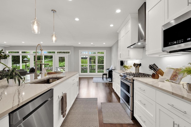 742 Charolais Dr, Slinger, WI 53086 - kitchen with appliances with stainless steel finishes, wall chimney range hood, recessed lighting, white cabinetry, and hanging light fixtures