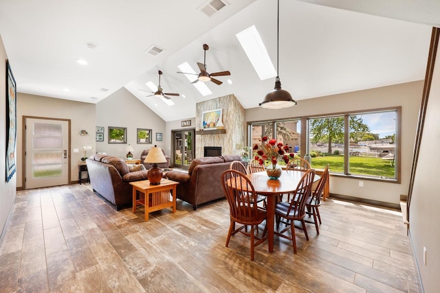 2830 Tomahawk Ct, Middleton, WI 53562 - dining space featuring ceiling fan, a stone fireplace, high vaulted ceiling, light wood-style flooring, and a skylight