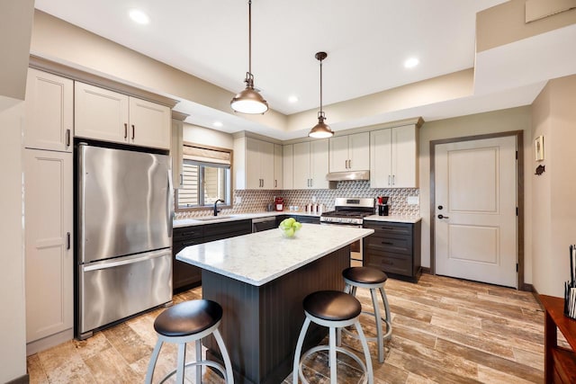 2830 Tomahawk Ct, Middleton, WI 53562 - kitchen featuring appliances with stainless steel finishes, a breakfast bar area, under cabinet range hood, decorative backsplash, and a kitchen island