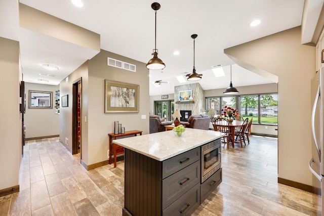 2830 Tomahawk Ct, Middleton, WI 53562 - kitchen featuring stainless steel microwave, a fireplace, recessed lighting, light wood finished floors, and hanging light fixtures