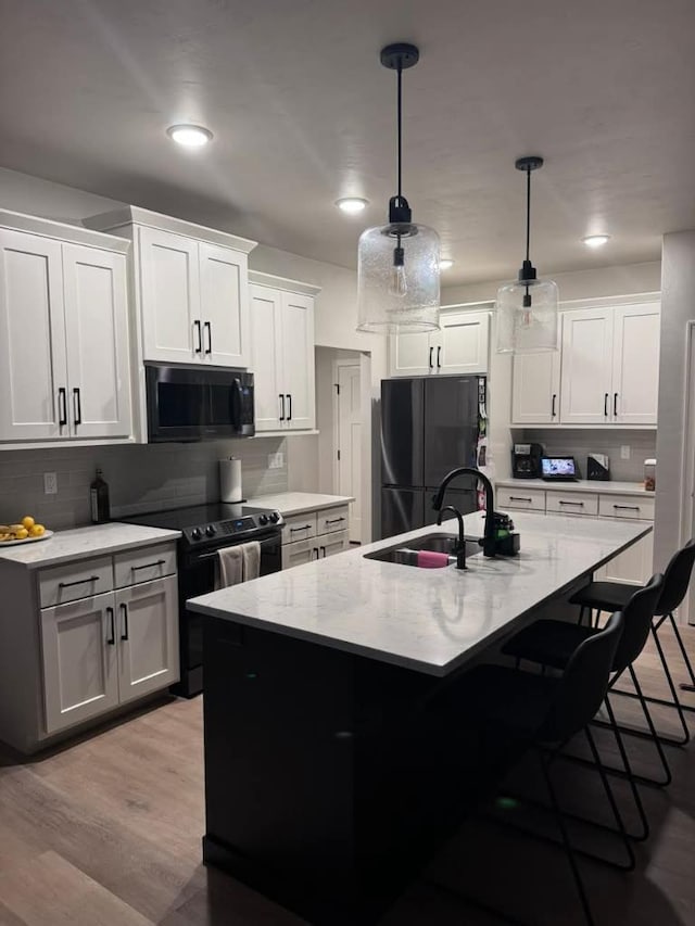 117 Cortland Ave, Casco, WI 54205 - kitchen with black appliances, a kitchen breakfast bar, tasteful backsplash, a kitchen island with sink, and pendant lighting