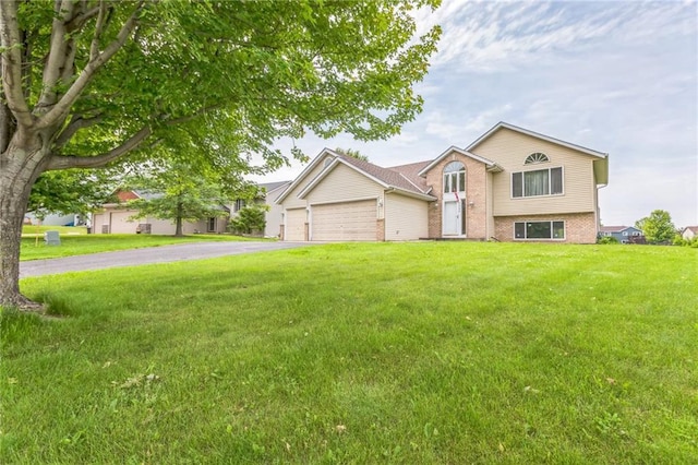 1566 Mallard Ave, Baldwin, WI 54002 - view of front facade featuring driveway, an attached garage, a front lawn, and brick siding