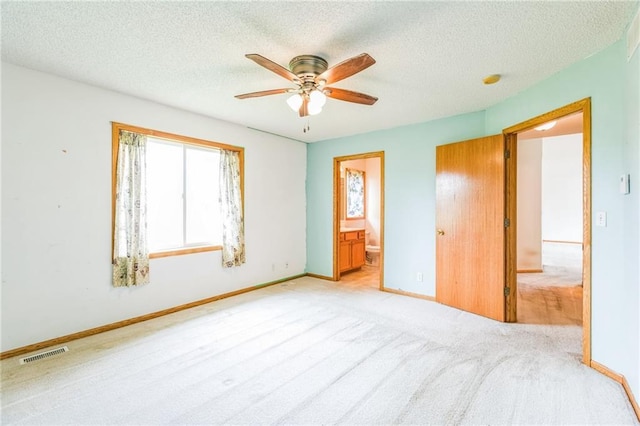 1566 Mallard Ave, Baldwin, WI 54002 - unfurnished bedroom featuring a textured ceiling, connected bathroom, light colored carpet, and a ceiling fan