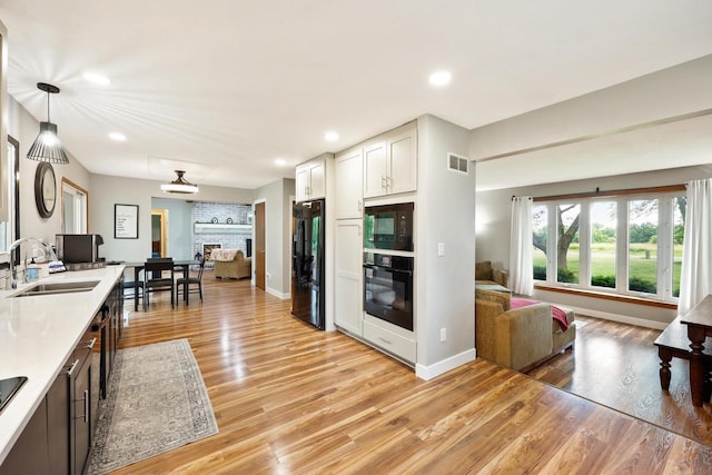 W365N7134 Mcmahon Rd, Oconomowoc, WI 53066 - kitchen with black appliances, light countertops, light wood-style floors, recessed lighting, and white cabinets