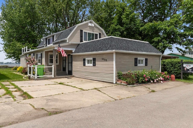 2963 Sunset Point Ln, Oshkosh, WI 54904 - dutch colonial with roof with shingles, a gambrel roof, concrete driveway, and covered porch