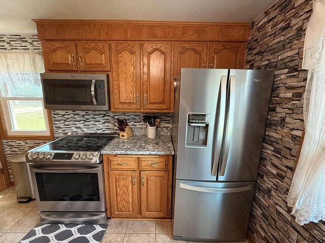810 10th St, Monroe, WI 53566 - kitchen with appliances with stainless steel finishes, brown cabinetry, light stone countertops, and backsplash