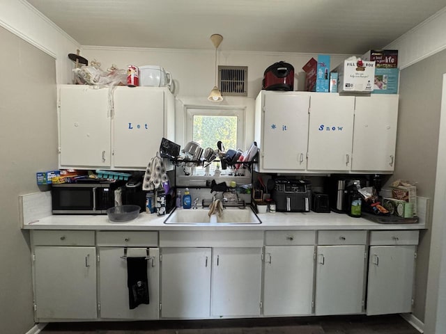 414 Barney St Unit 418, Waukesha, WI 53186 - kitchen with stainless steel microwave, light countertops, white cabinetry, and crown molding