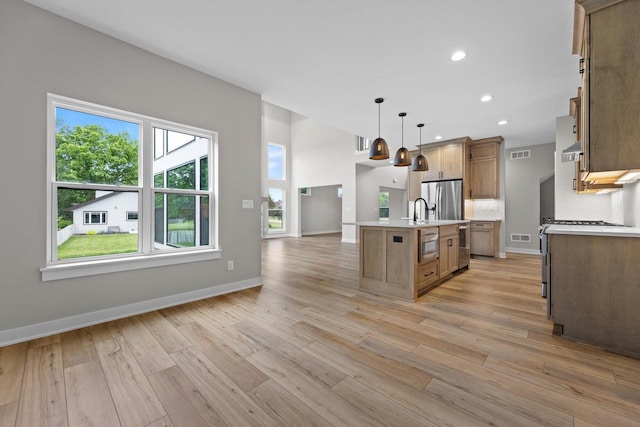 N65W34963 Baltic Pass, Oconomowoc, WI 53066 - kitchen featuring stainless steel fridge with ice dispenser, light countertops, light wood finished floors, a kitchen island with sink, and open floor plan