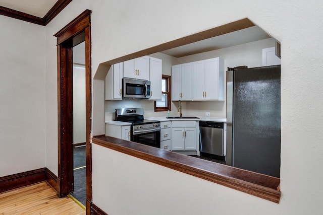 1140 Bluff St, Beloit, WI 53511 - kitchen with stainless steel appliances, light wood-type flooring, white cabinetry, and crown molding