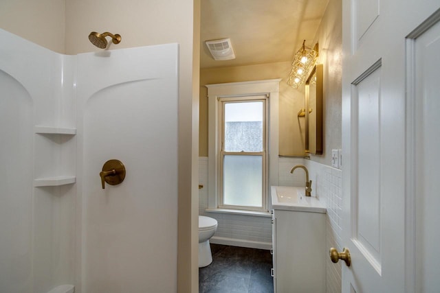 1140 Bluff St, Beloit, WI 53511 - bathroom with vanity, a shower, tile walls, and a wainscoted wall