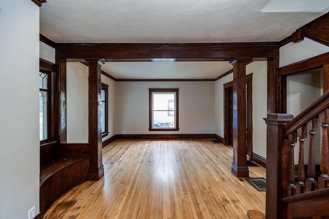 1140 Bluff St, Beloit, WI 53511 - spare room featuring ornate columns, light wood-style floors, crown molding, and stairs