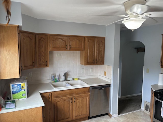 4945 W Tesch Ave, Milwaukee, WI 53220 - kitchen featuring appliances with stainless steel finishes, arched walkways, brown cabinetry, backsplash, and light countertops