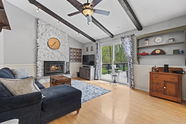 611 Mount Snowdon Rd, Wales, WI 53183 - living room with wood finished floors, a stone fireplace, wainscoting, a ceiling fan, and track lighting