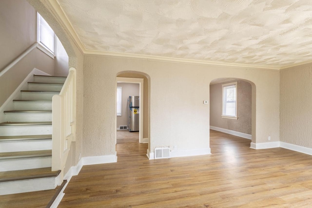 4366 N 25th St, Milwaukee, WI 53209 - empty room featuring arched walkways, a textured wall, stairway, crown molding, and wood finished floors