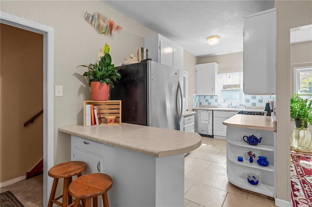 110 1st Ave, Balsam Lake, WI 54005 - kitchen featuring appliances with stainless steel finishes, a peninsula, light countertops, and light tile patterned flooring