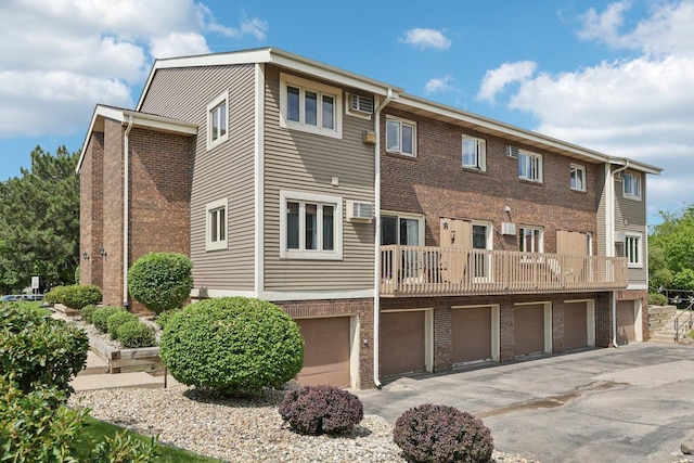 1603 Mckenna Blvd, Madison, WI 53711 - rear view of property featuring asphalt driveway, brick siding, a garage, and a balcony