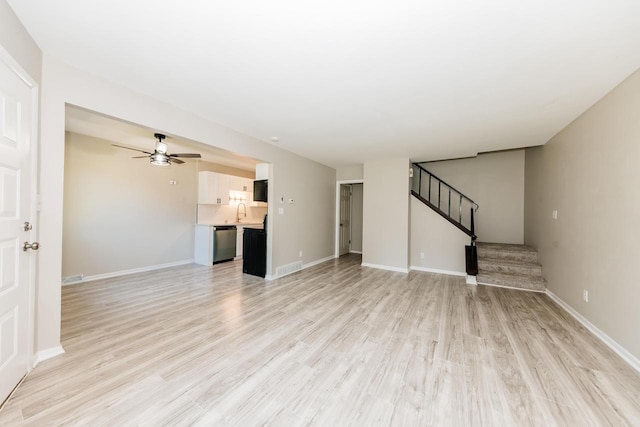 W169N11492 Biscayne Dr, Germantown, WI 53022 - unfurnished living room featuring a ceiling fan, stairway, and light wood-style flooring