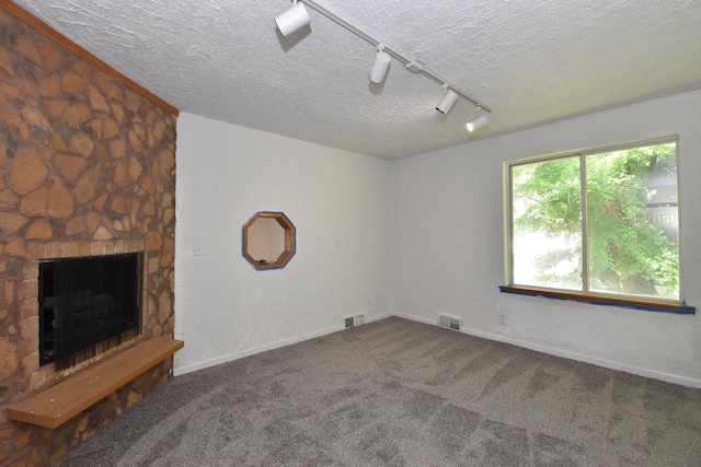 1600 Winslow St, Racine, WI 53404 - carpeted empty room with a textured ceiling, track lighting, and a stone fireplace
