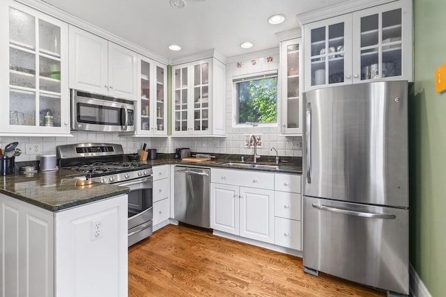 1853 N 83rd St, Wauwatosa, WI 53213 - kitchen featuring stainless steel appliances, white cabinets, glass insert cabinets, decorative backsplash, and light wood-style flooring