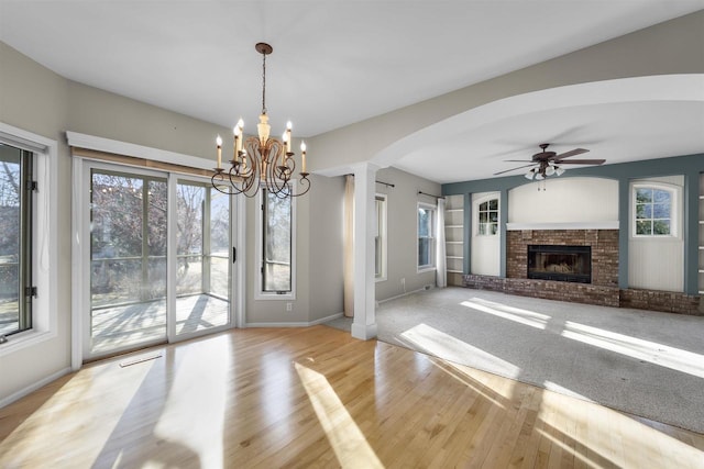 4227 Savannah Ct, Middleton, WI 53562 - unfurnished living room featuring arched walkways, a brick fireplace, wood finished floors, a chandelier, and a ceiling fan