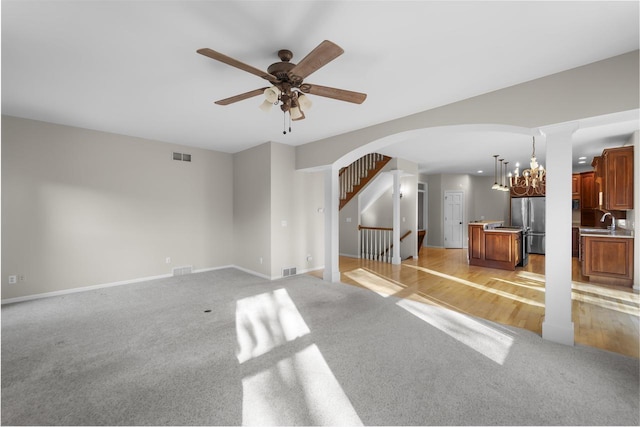 4227 Savannah Ct, Middleton, WI 53562 - unfurnished living room featuring light carpet, arched walkways, ceiling fan, a chandelier, and stairs