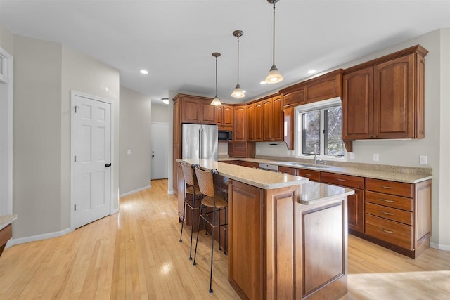 4227 Savannah Ct, Middleton, WI 53562 - kitchen featuring a breakfast bar area, a kitchen island, light wood-type flooring, pendant lighting, and brown cabinetry