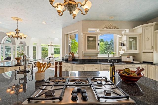 1626 Fox Hollow Ln, Cedarburg, WI 53012 - kitchen with cream cabinetry, a chandelier, stainless steel gas stovetop, glass insert cabinets, and hanging light fixtures