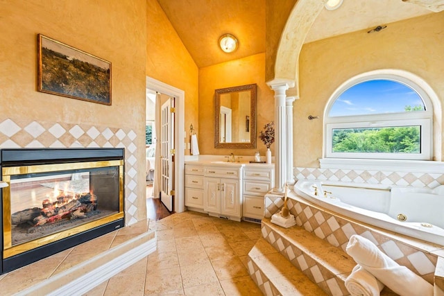 1626 Fox Hollow Ln, Cedarburg, WI 53012 - bathroom featuring a whirlpool tub, vanity, vaulted ceiling, a multi sided fireplace, and decorative columns