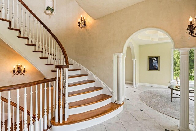 1626 Fox Hollow Ln, Cedarburg, WI 53012 - stairway featuring arched walkways, ornate columns, a towering ceiling, and tile patterned flooring
