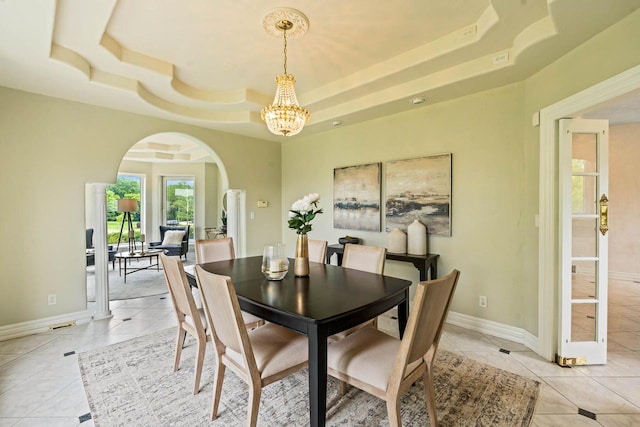 1626 Fox Hollow Ln, Cedarburg, WI 53012 - dining space with arched walkways, a raised ceiling, a chandelier, and light tile patterned floors