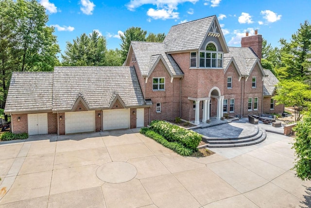N69W29753 Ridgeview Ct, Hartland, WI 53029 - view of front of property with brick siding, a chimney, driveway, and an attached garage