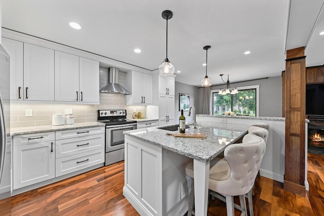 836 Pilgrim Pkwy, Elm Grove, WI 53122 - kitchen with stainless steel range with electric cooktop, wall chimney range hood, white cabinetry, backsplash, and a kitchen bar