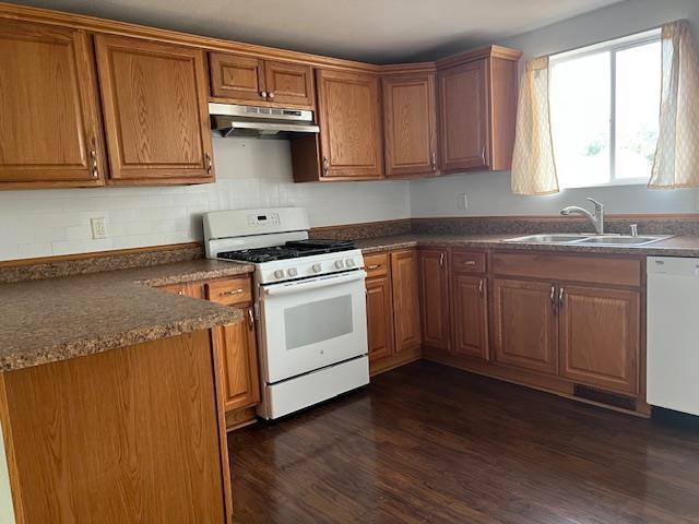 1153 W 7th Ave, Oshkosh, WI 54902 - kitchen with white appliances, under cabinet range hood, brown cabinets, and dark countertops