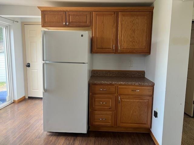 1153 W 7th Ave, Oshkosh, WI 54902 - kitchen with freestanding refrigerator, dark countertops, brown cabinetry, and dark wood-style flooring