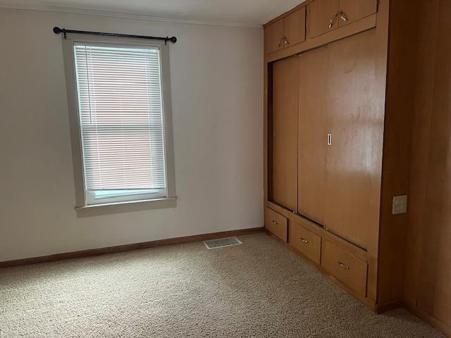 1153 W 7th Ave, Oshkosh, WI 54902 - unfurnished bedroom with ornamental molding, light carpet, and a closet