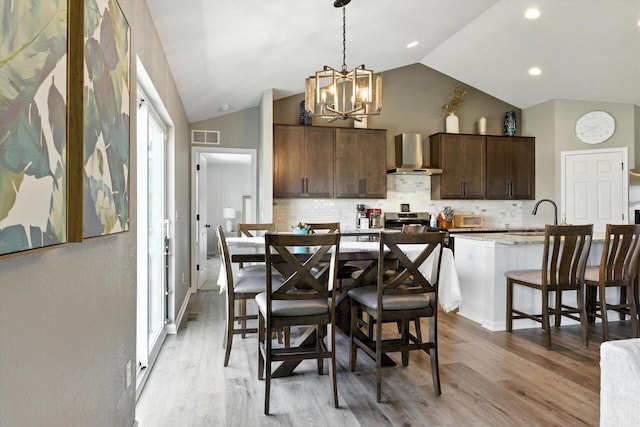 1143 Juniper Ln, Oconomowoc, WI 53066 - dining space featuring a chandelier, vaulted ceiling, and light wood-style floors