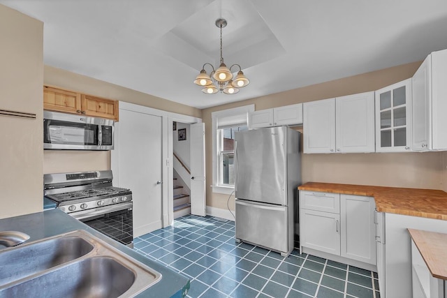1235 Grove Ave, Racine, WI 53405 - kitchen featuring stainless steel appliances, white cabinetry, glass insert cabinets, pendant lighting, and a chandelier