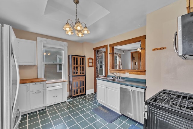 1235 Grove Ave, Racine, WI 53405 - kitchen with appliances with stainless steel finishes, a chandelier, white cabinets, decorative light fixtures, and dark tile patterned floors