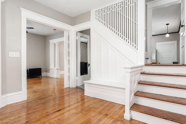 716 Vernon Ave, Beloit, WI 53511 - staircase featuring radiator heating unit, hardwood / wood-style floors, and ornate columns