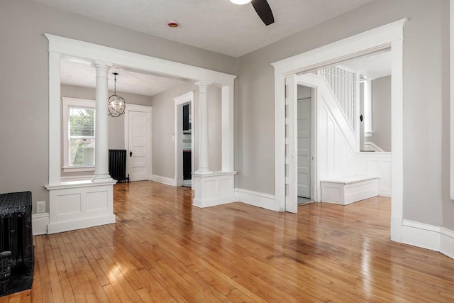 716 Vernon Ave, Beloit, WI 53511 - unfurnished living room with light wood finished floors, ornate columns, ceiling fan, and radiator