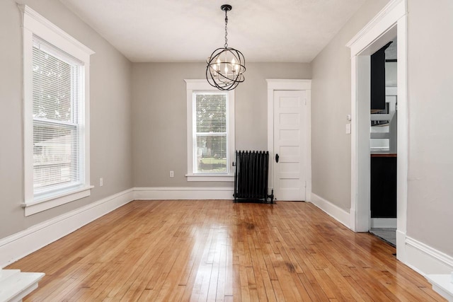 716 Vernon Ave, Beloit, WI 53511 - unfurnished dining area featuring radiator heating unit, a chandelier, and light wood-style flooring