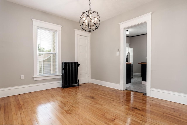 716 Vernon Ave, Beloit, WI 53511 - spare room with radiator heating unit, light wood-type flooring, and a chandelier
