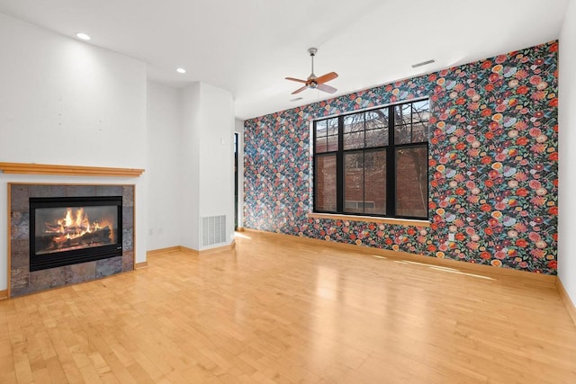 530 W Doty St Unit 107, Madison, WI 53703 - unfurnished living room with wallpapered walls, wood finished floors, ceiling fan, a tiled fireplace, and recessed lighting