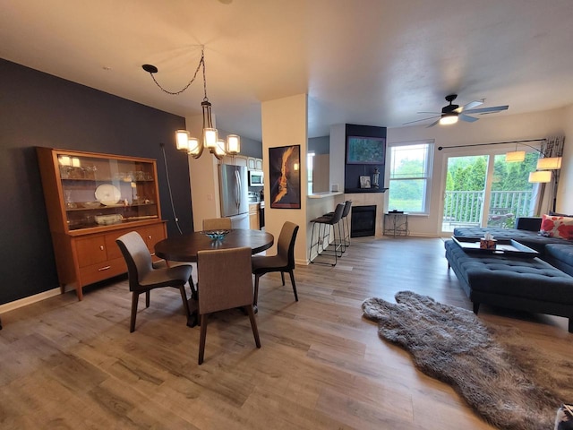 N113W16241 Sylvan Cir Unit 110, Germantown, WI 53022 - dining space featuring light wood-type flooring, ceiling fan, a tile fireplace, and a chandelier