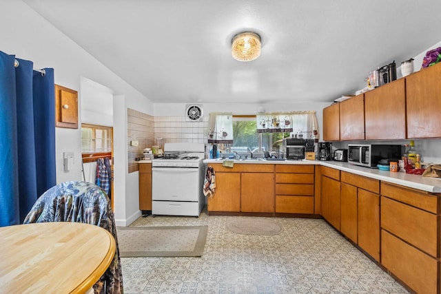 W914 Madsen Rd, Marinette, WI 54143 - kitchen with white gas range, stainless steel microwave, light countertops, and brown cabinets