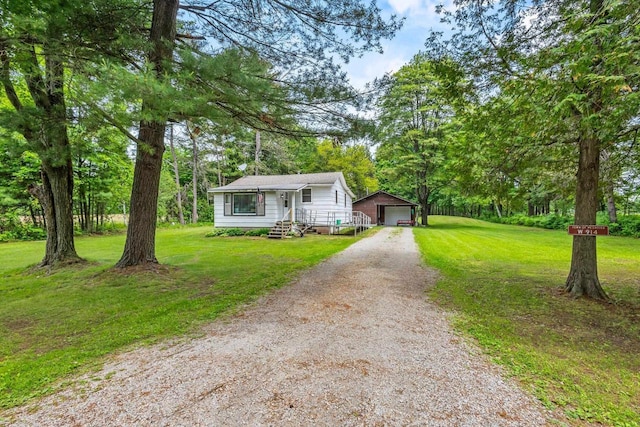 W914 Madsen Rd, Marinette, WI 54143 - bungalow-style home featuring an outbuilding, dirt driveway, a garage, and a front lawn