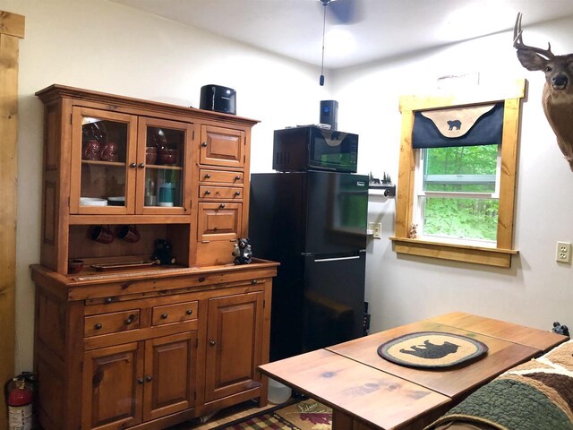 W15036 Poachers Run Ln, Athelstane, WI 54101 - kitchen with refrigerator, black microwave, glass insert cabinets, and brown cabinetry